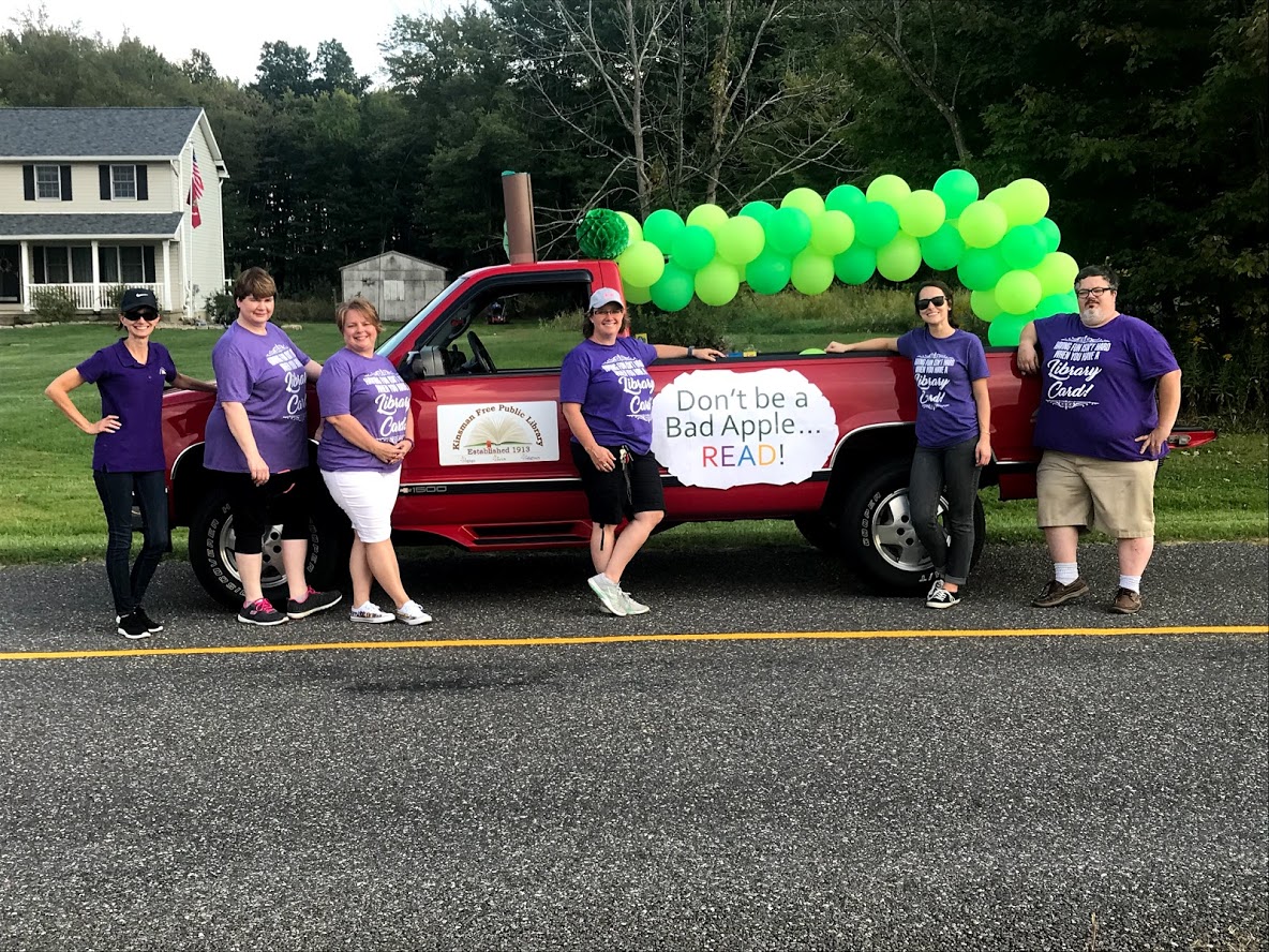 People standing in front of a truck with ballons and a sign that says "Don't be a bad apple...read!"